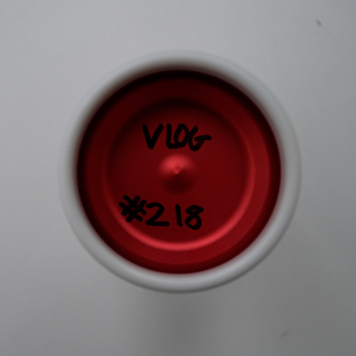 A top-down view of a red and white yo-yo with handwritten black markings reading 'V1.06' and '#2.