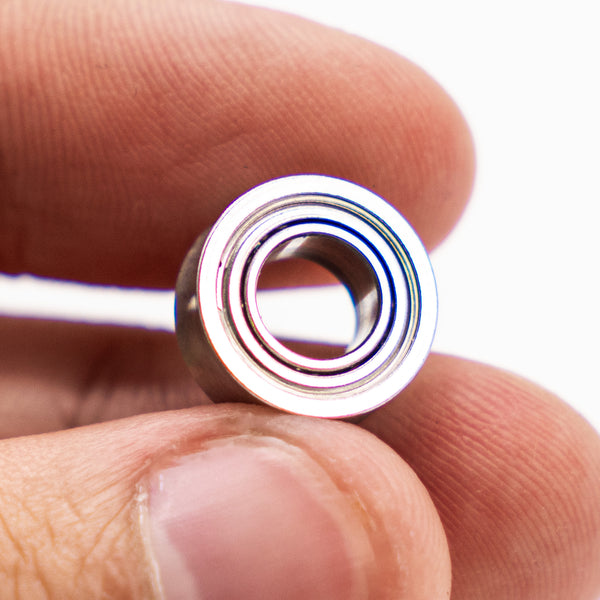 OFFSET Competition Bearing held between two fingers, showing the concave inner groove